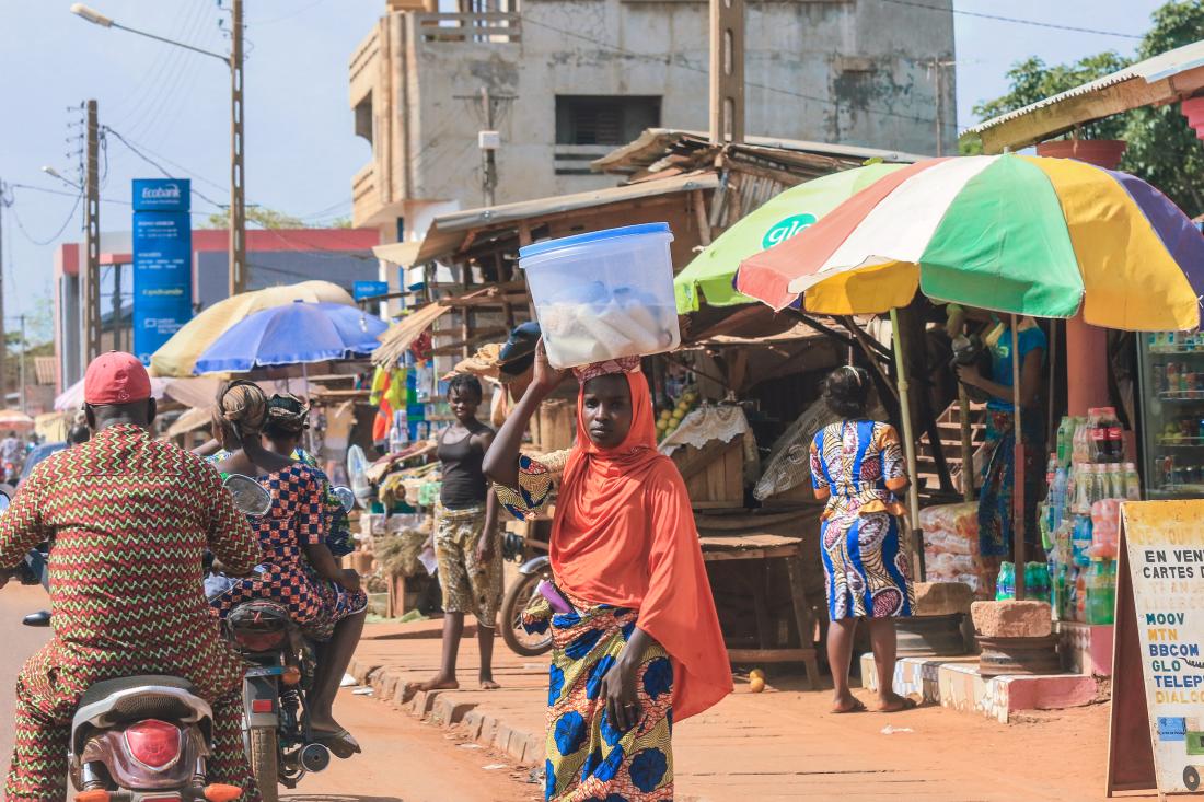 A woman carries goods through a market in Benin.