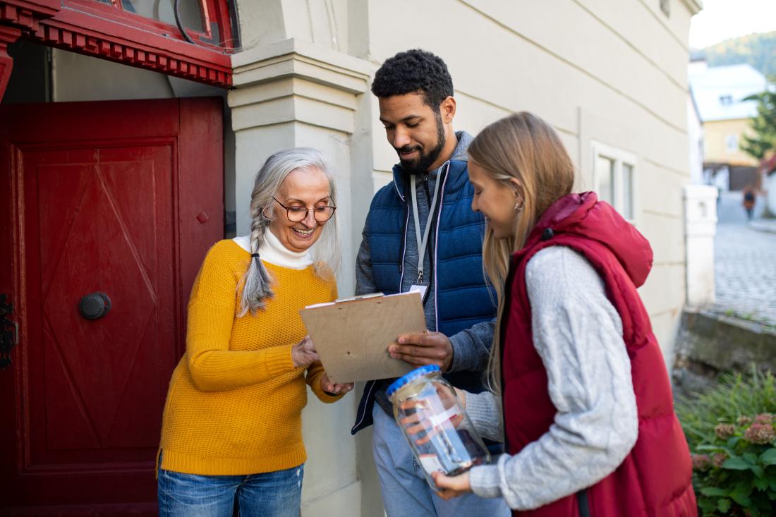 Two volunteer canvassers speak with woman in yellow shirt about voting and how it can lead to a habit in the United States.