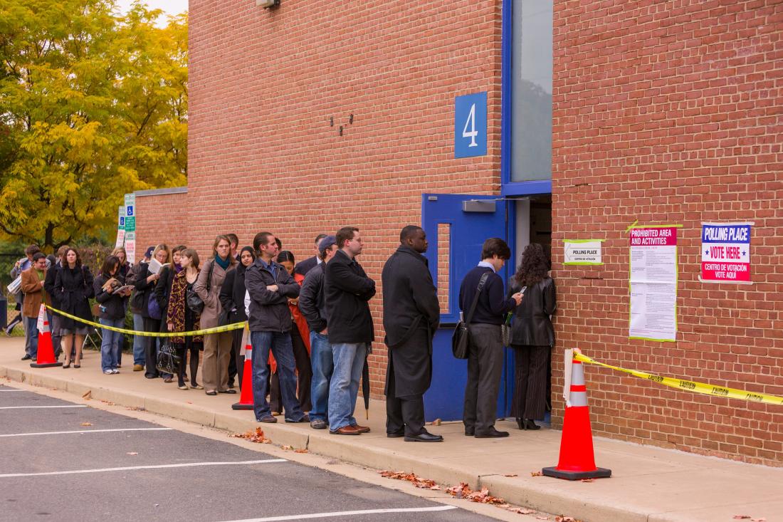 Line of people showing voter turnout against brick building in the United States.