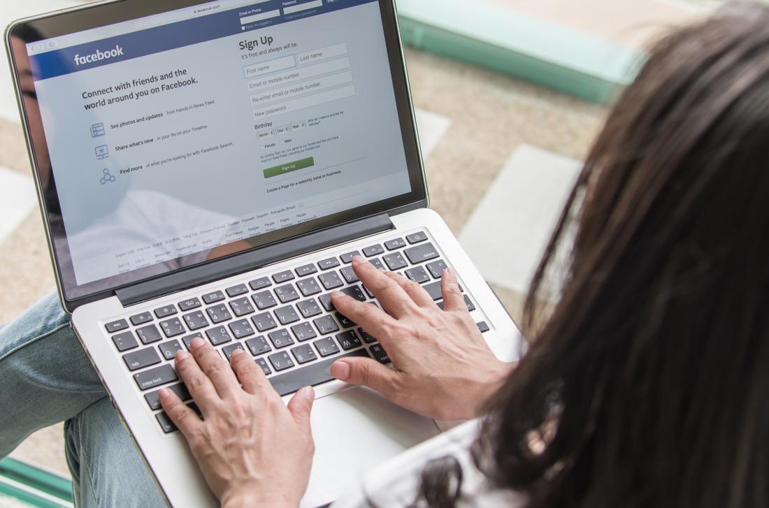 A person logging into Facebook online on their laptop device in the United States
