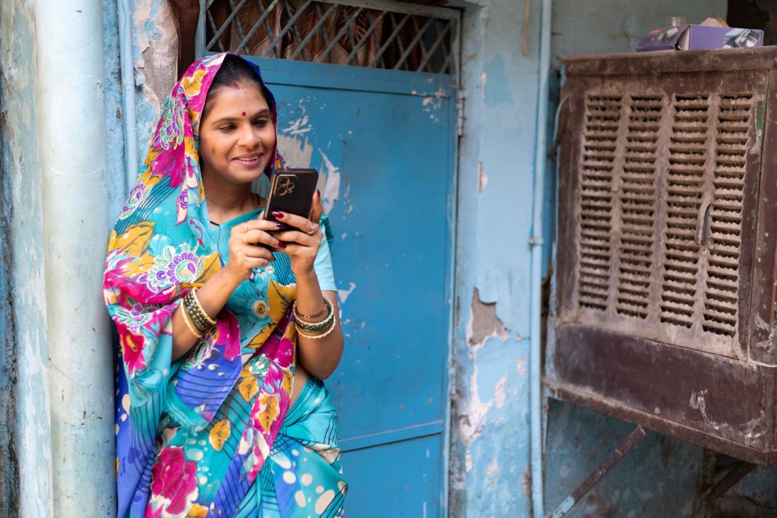Woman with colorful headscarf looks at mobile phone in Andhra Pradesh
