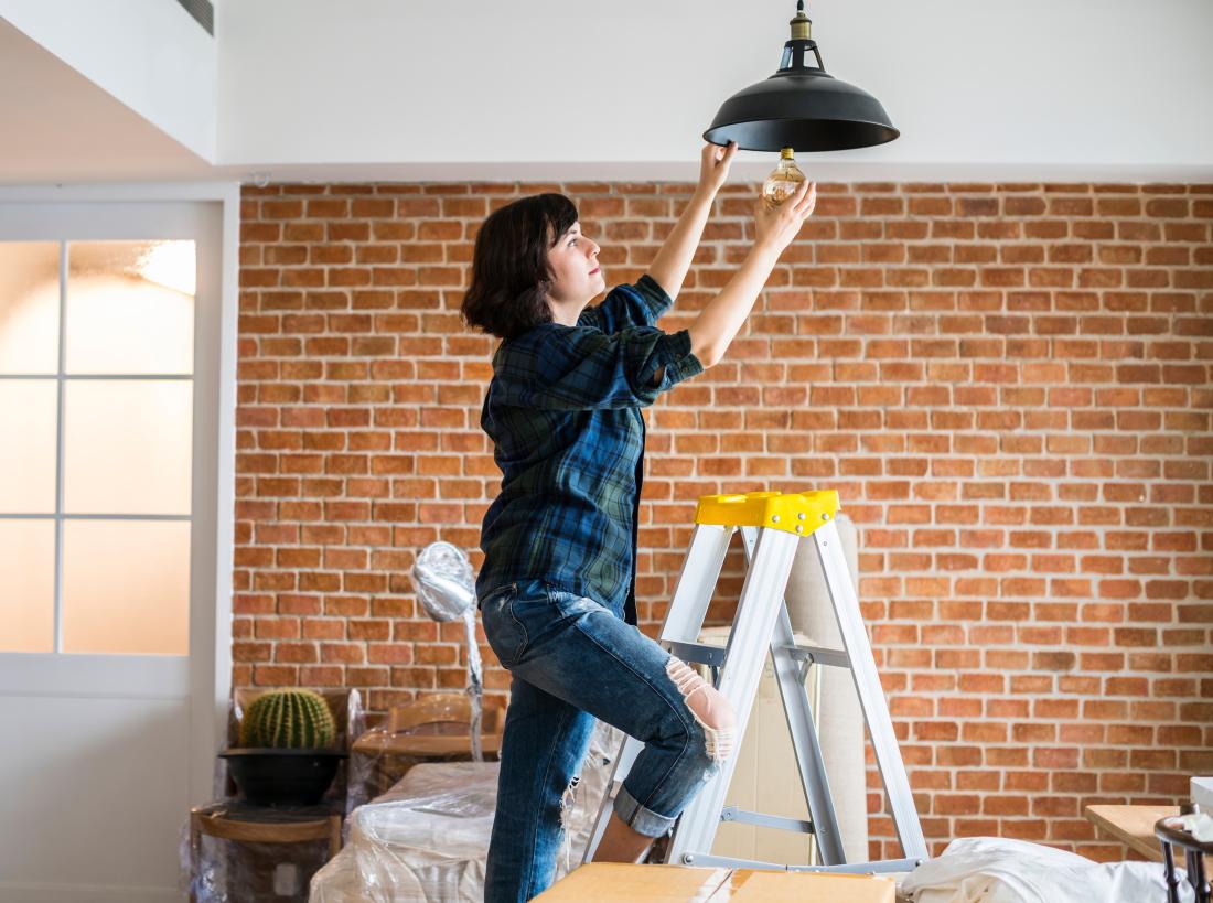 Brunette woman changes energy efficient lightbulb in the United States.