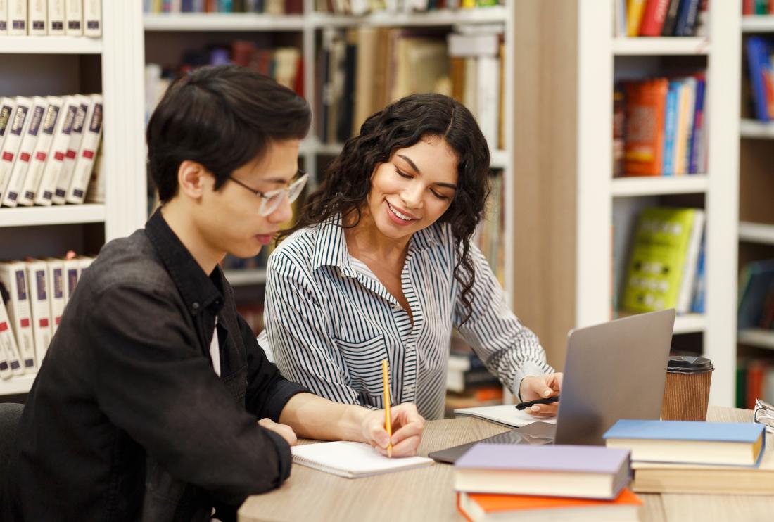 A woman coaching a student in a library in the United States.