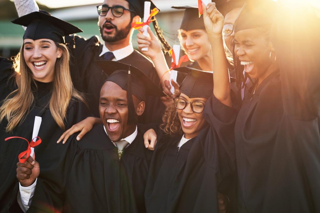 Achievement program college students wearing caps and gowns with diplomas in hand in the United States