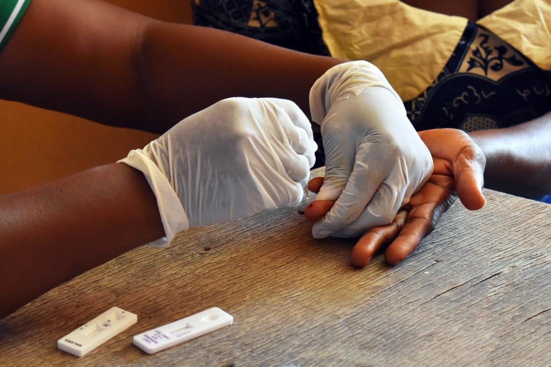 Subsidized malaria diagnostic test being administered by health worker wearing gloves in Africa