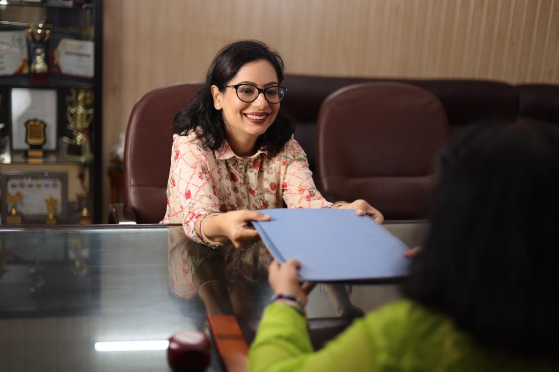 A school principal happily hands an evaluation report to a teacher in the United States