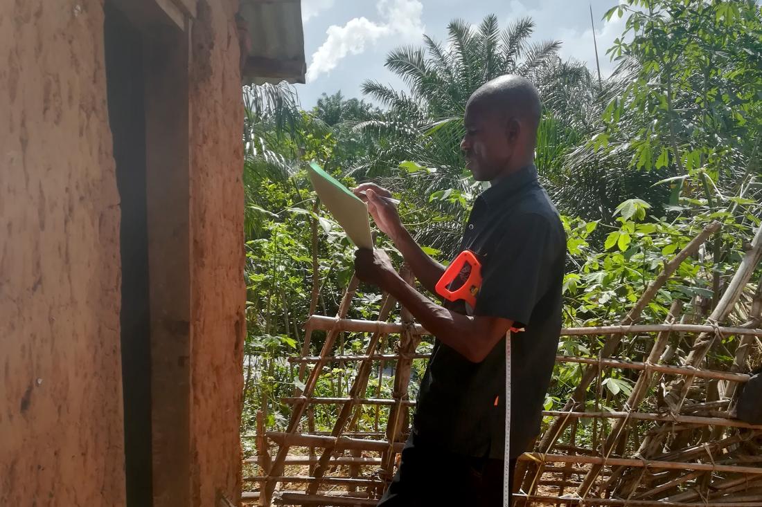 A man holding a folder stands in front of a house