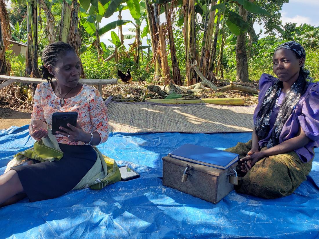 Two women are interviewed with the community lending ledger box in front of them.