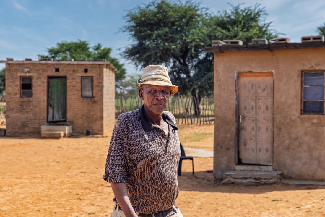 Elderly man standing in front of houses 