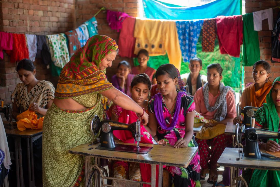 woman instructs children at sewing machine