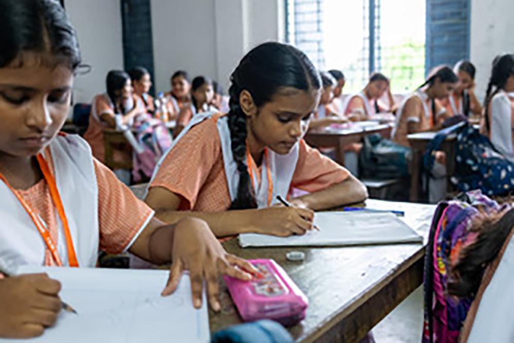 Students in classrooms, writing in notebooks.