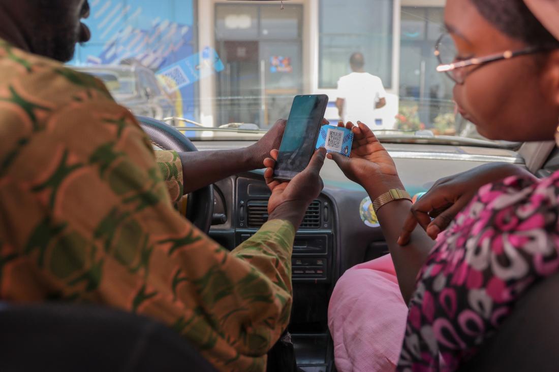 A taxi passenger uses a Wave card to make a digital fare payment, while the driver scans the QR code using a mobile phone in Dakar, Senegal.