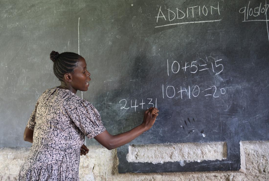 A teacher writes on chalk board in Kenya.