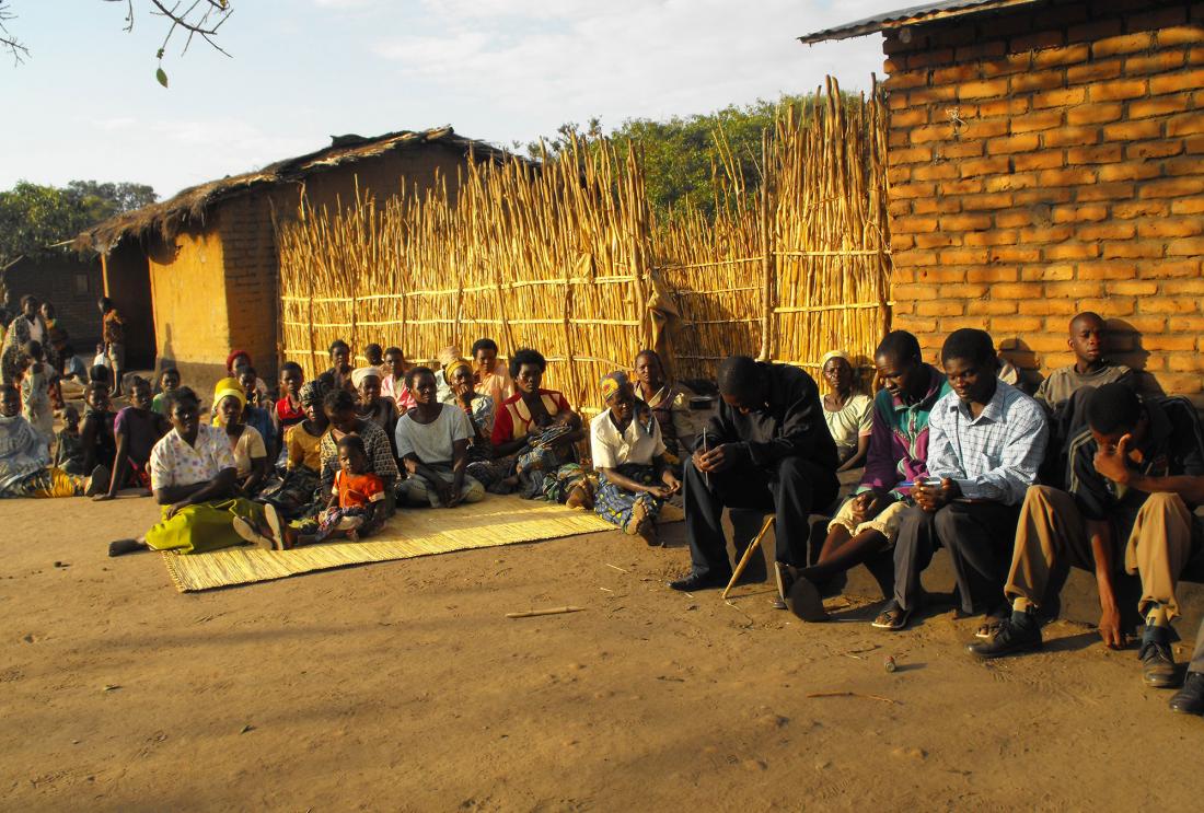 Men and women sit in Malawi village