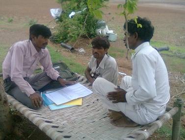 Three men talking over paperwork outdoors