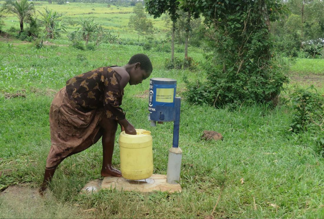 Young girl chlorinating her water at a point-of-use public dispenser, Kenya, 2015