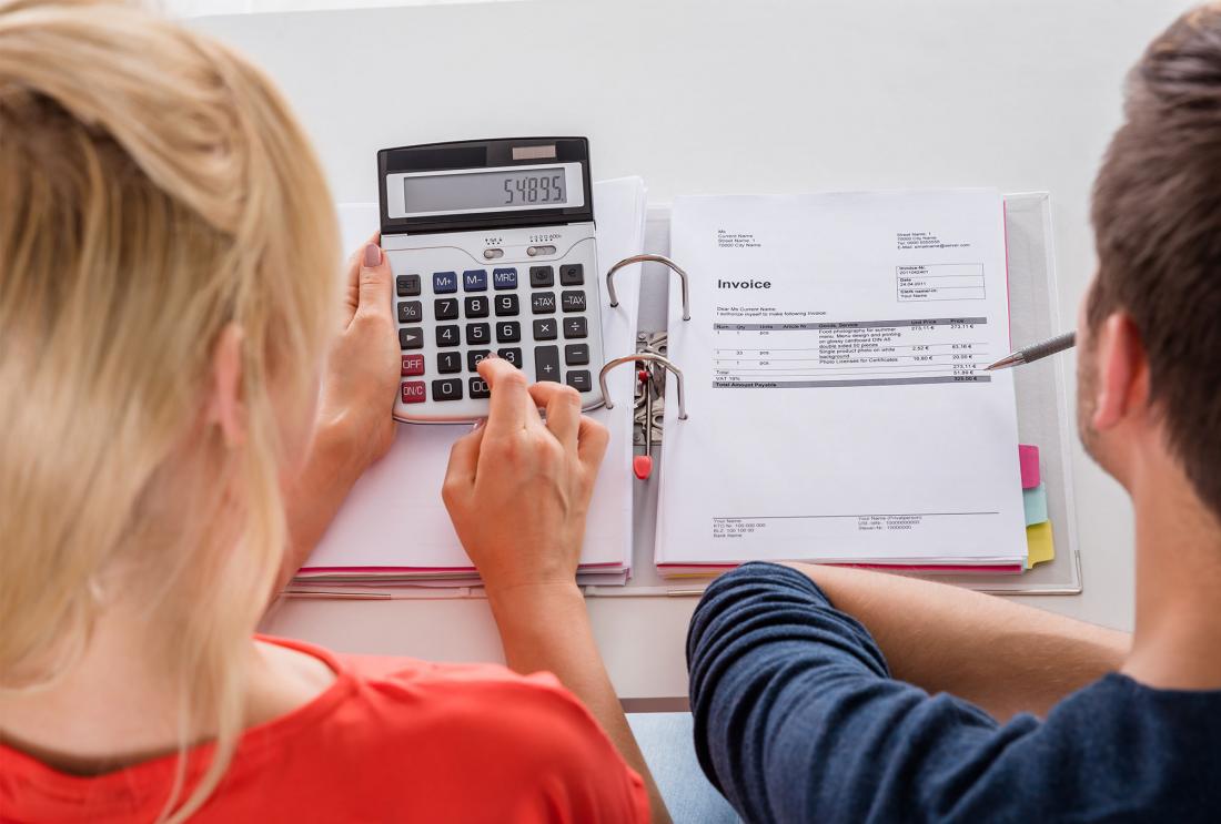 Two people look at calculator and invoice