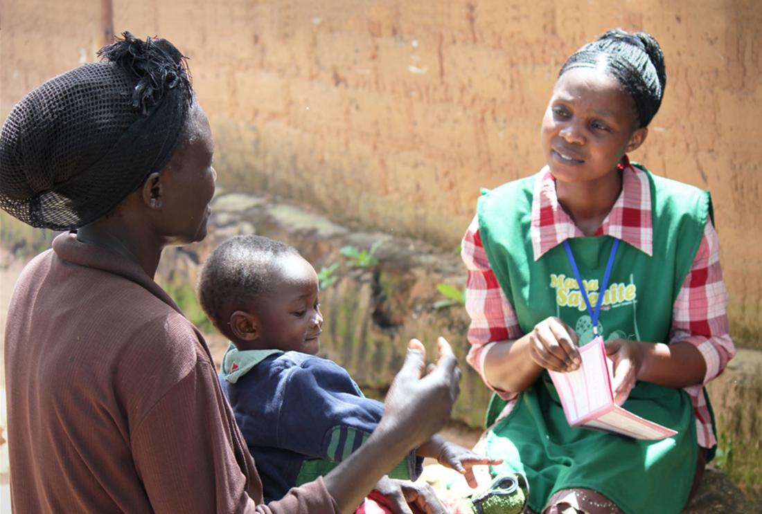 Woman in uniform talks to woman with baby in her lap