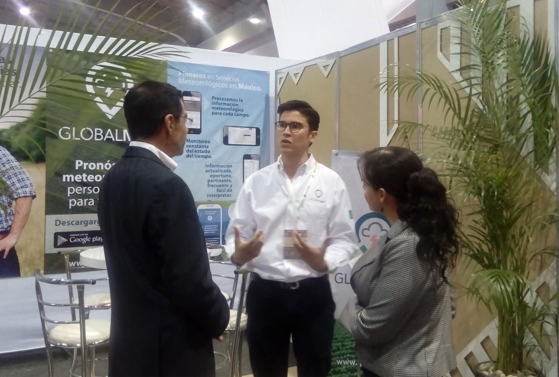 Man speaks to two judges in front of a booth with promotional materials for Globalmet