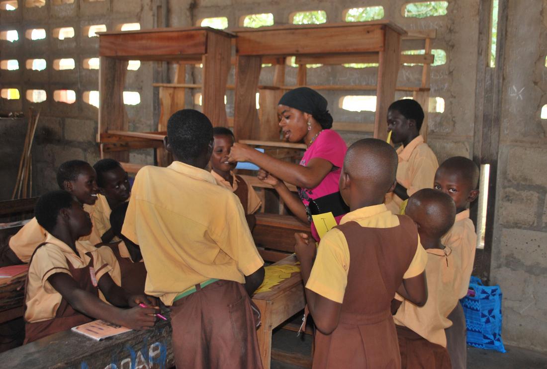 Students gather around their teacher in Ghana.