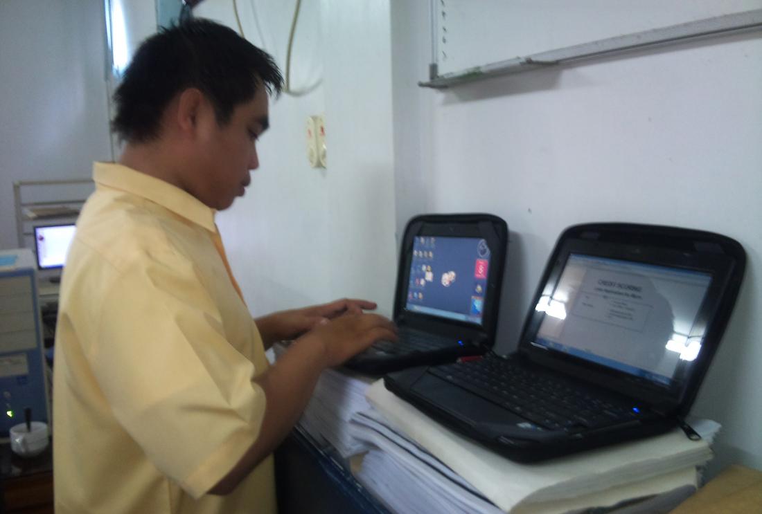 Man in yellow shirt types on two small laptops