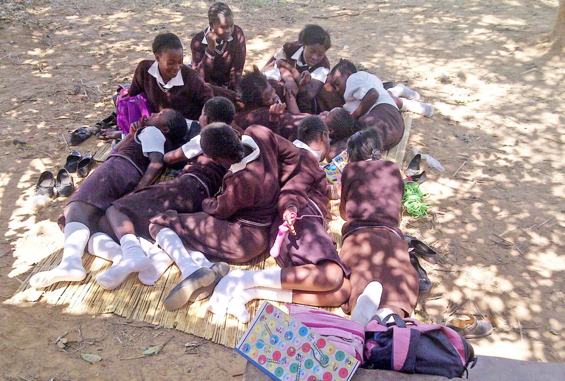 Girls in uniforms lounge outside on mat