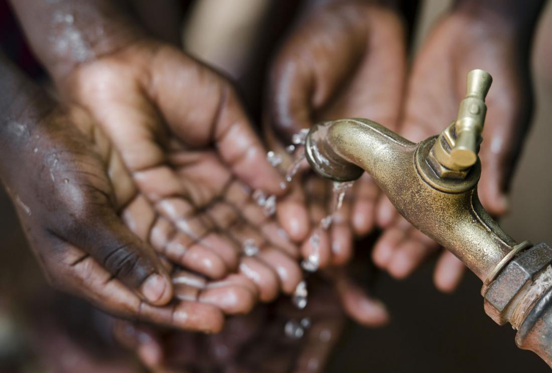Hands reaching for water from a spigot in Ethiopia.