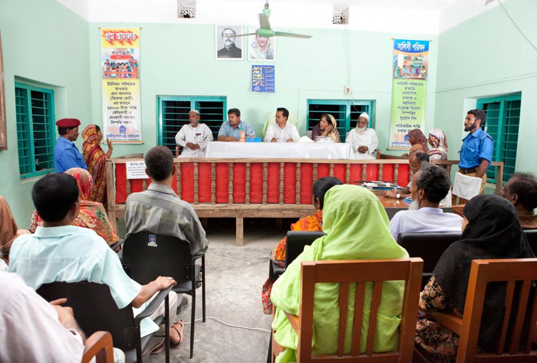 Panel of five judges listens to woman testifying in front of small crowd