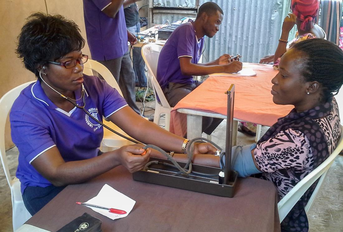 A health care worker takes a patient's blood pressure