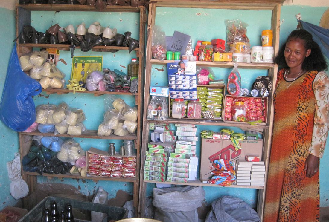 Woman in long dress next to two shelving units stacked with shoes and household wares