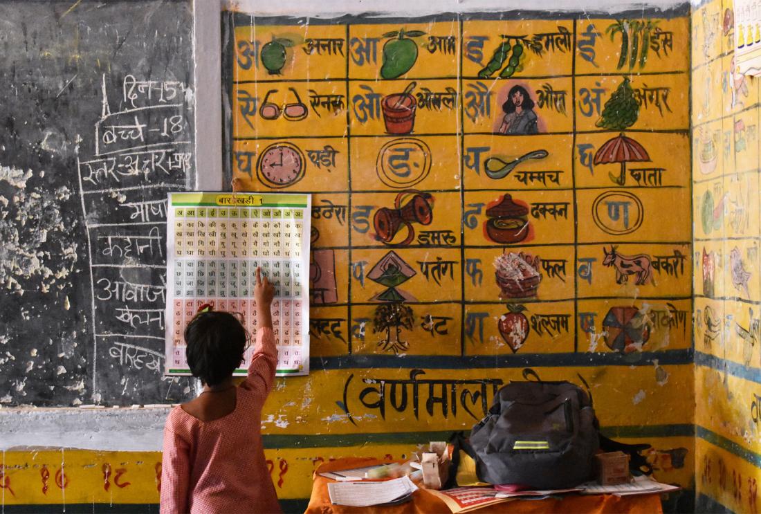 A child learning at a chart on the wall in a classroom.