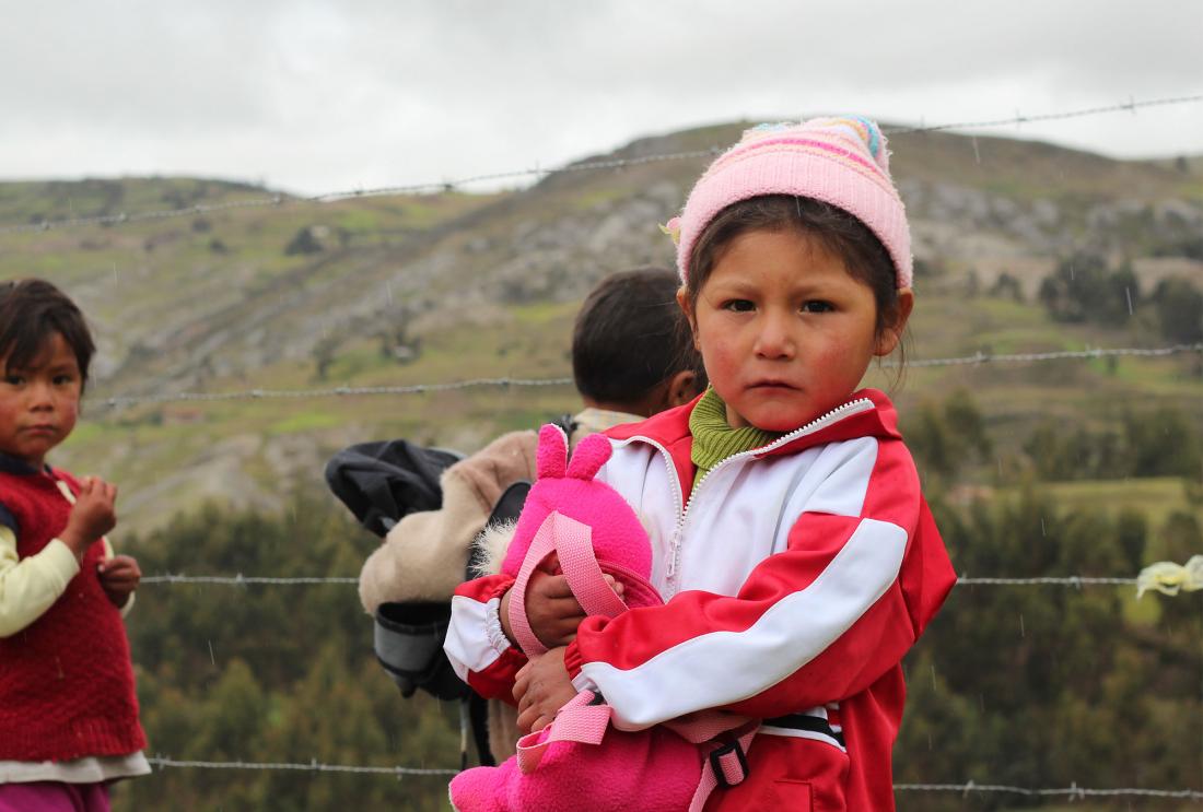 Young girl in pink jacket and hat outside in rural Peru