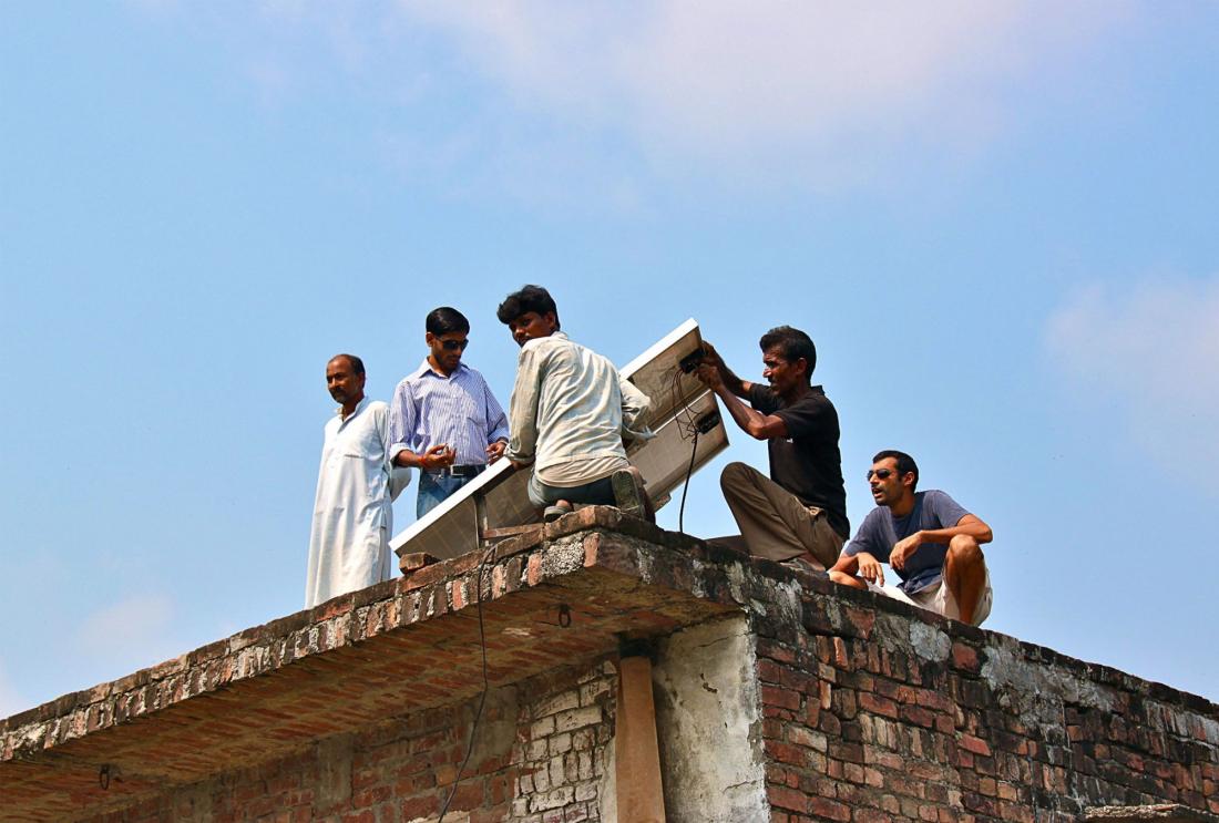 Group of men on the roof of a building installing solar panel