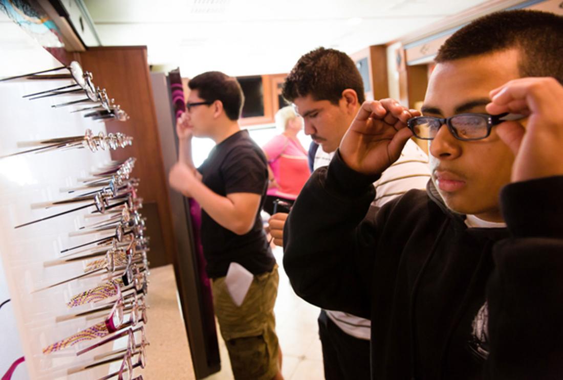 Three young men try on glasses