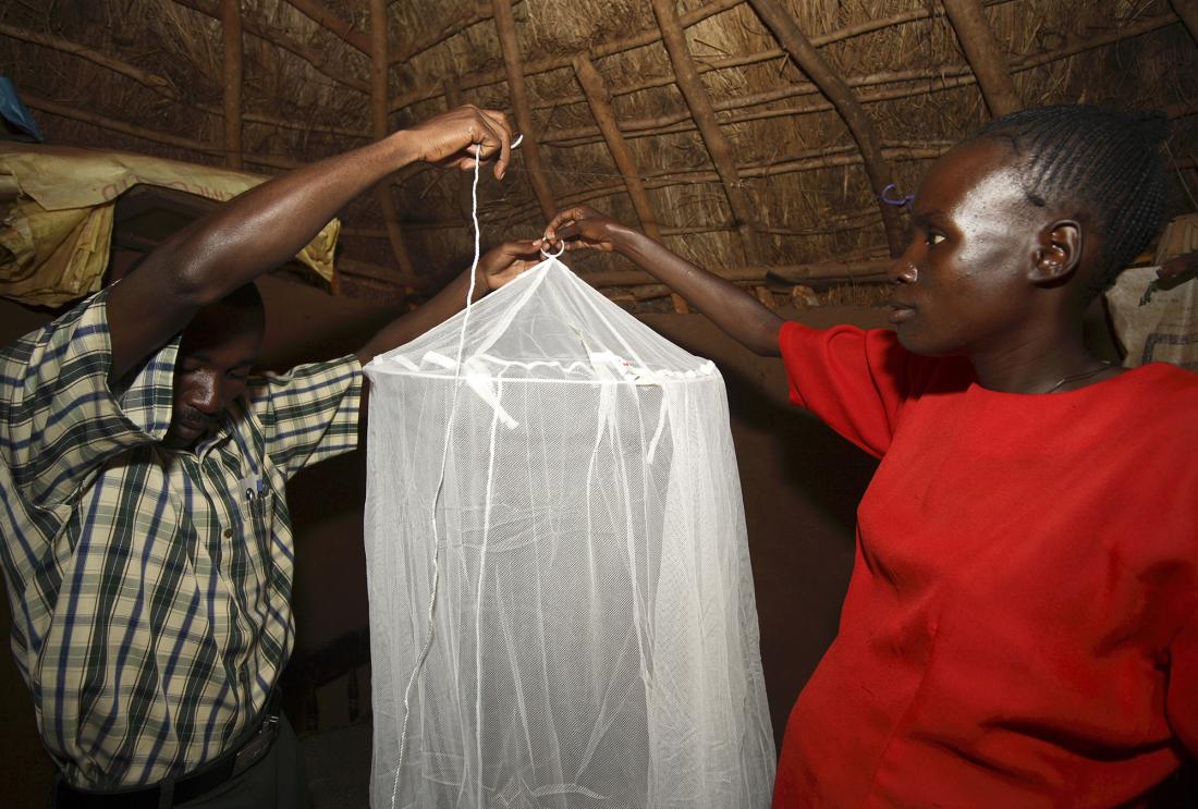 A man and woman assemble a bed net to provide malaria protection.