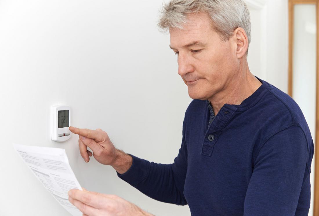 Man adjusts thermostat