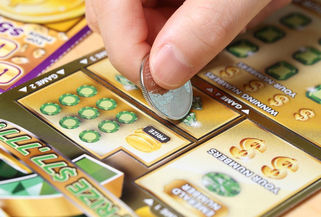 Person using coin to scratch lottery ticket