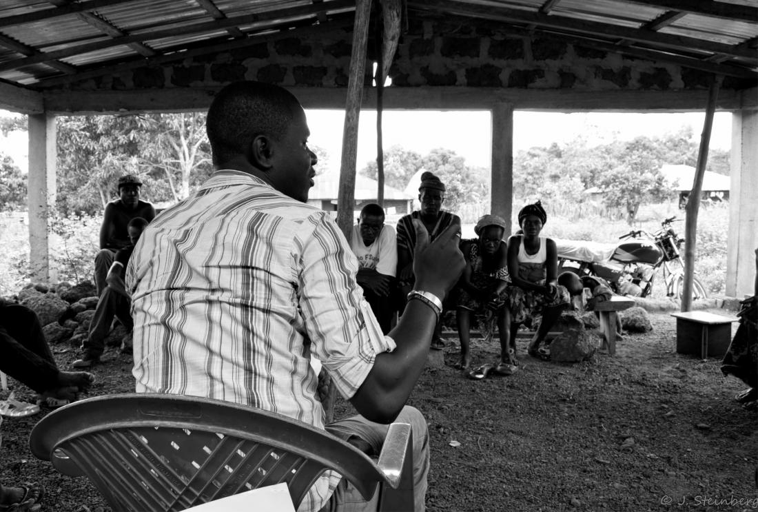Man leads a discussion under an outdoor meeting tent
