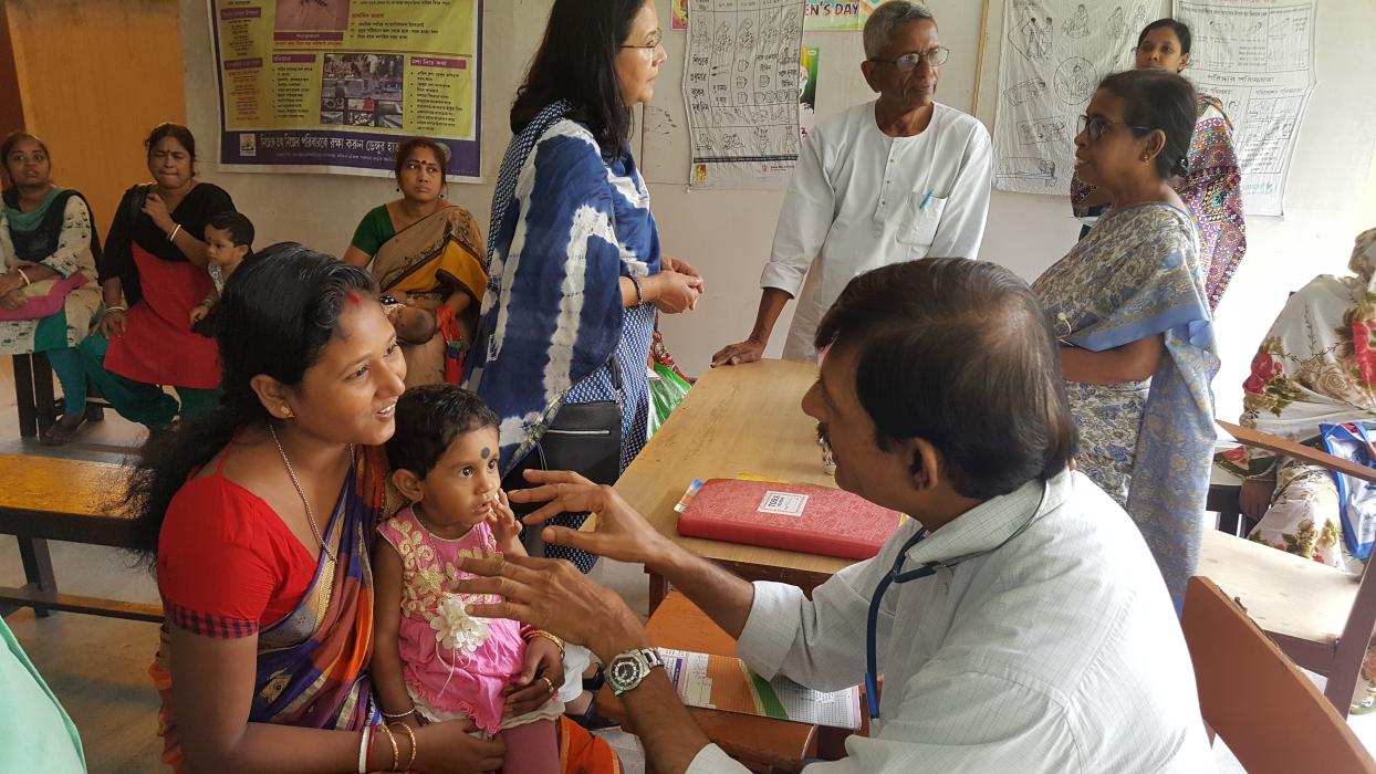 A medical worker immunizes a child while her mother holds her.