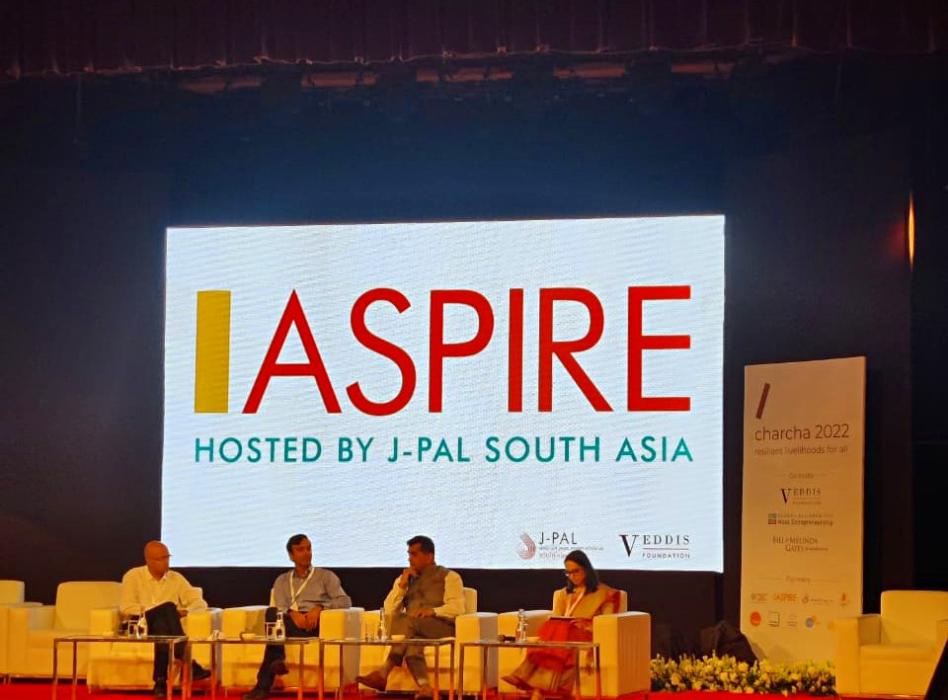 Panelists engage in a discussion on stage in front of a large ASPIRE screen during the launch of ASPIRE at the Charcha 2022 