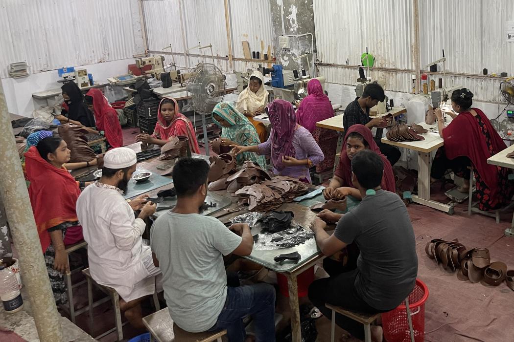 Several men and women sitting working in a sewing factory