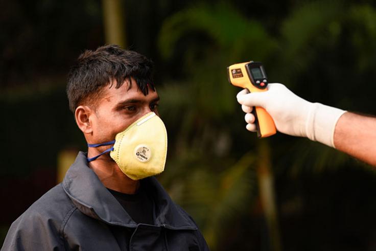 Temperature gun tests a man wearing a mask for COVID-19 in India