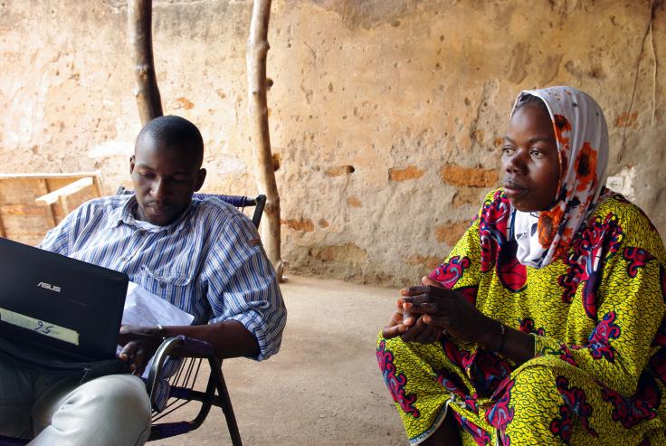 Photo of a woman sitting next to a man surveying her with a laptop in Mali