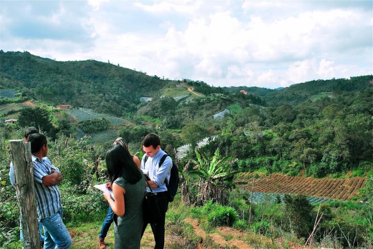 Michael Eddy and two women hold clipboards and speak with two men on a hillside