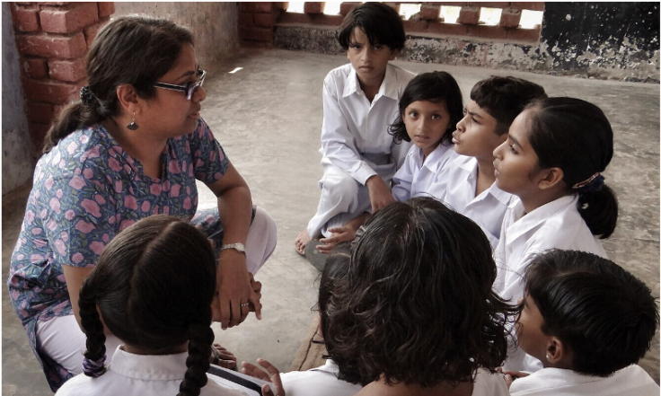 A teacher speaks to a circle of students in India