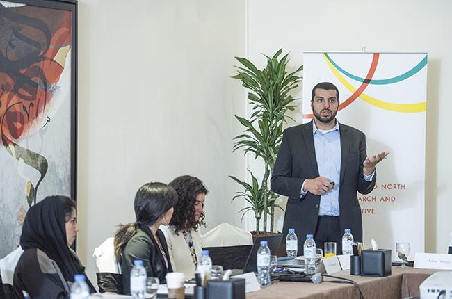 Adam Osman standing in front of three women presenting