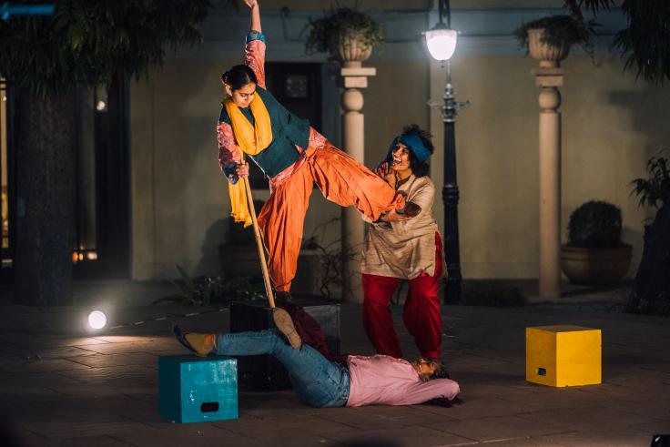 An actor in a theatre presentation balancing on one leg being supported by another actor