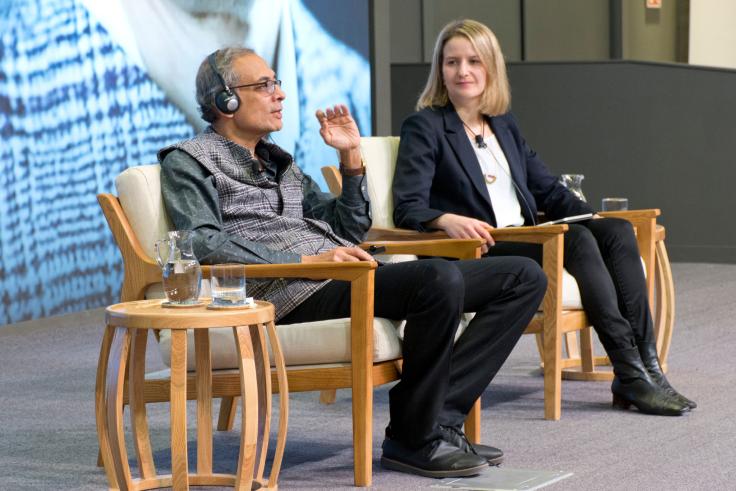 Abhijit Banerjee speaking on stage next to Monica Martinez-Bravo. 