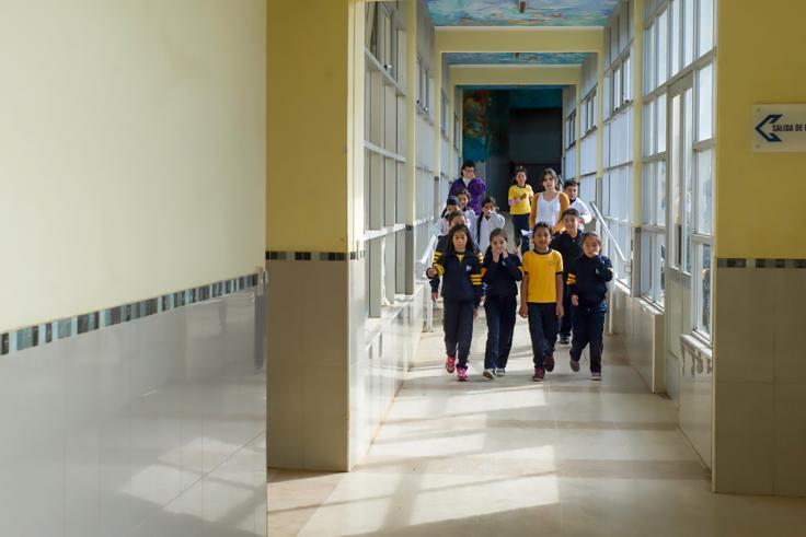 Elementary students walking down a long hallway