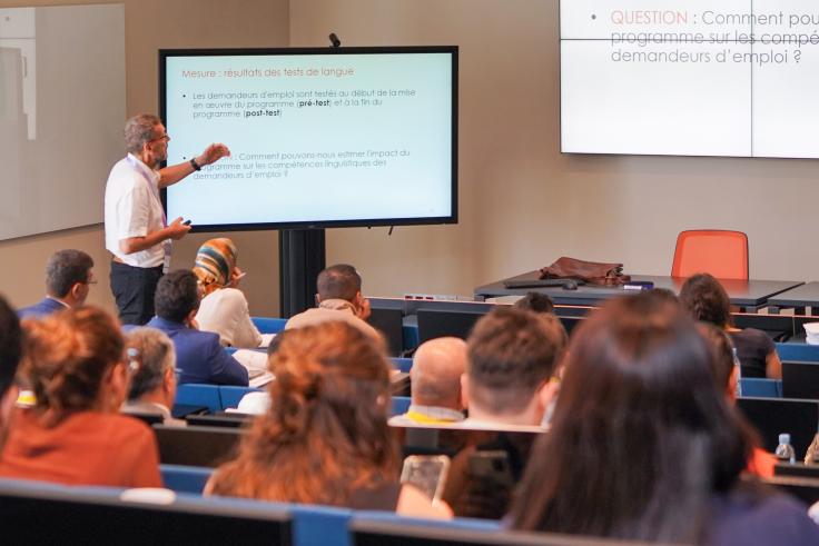 Man standing in front of slide presenting in front of a large audience